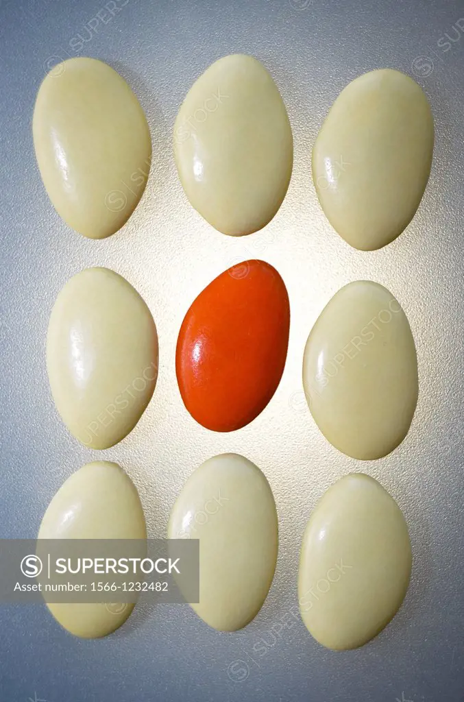 White stones surrounding a stone orange. Fund backlit. Message difference between an individual and a group.
