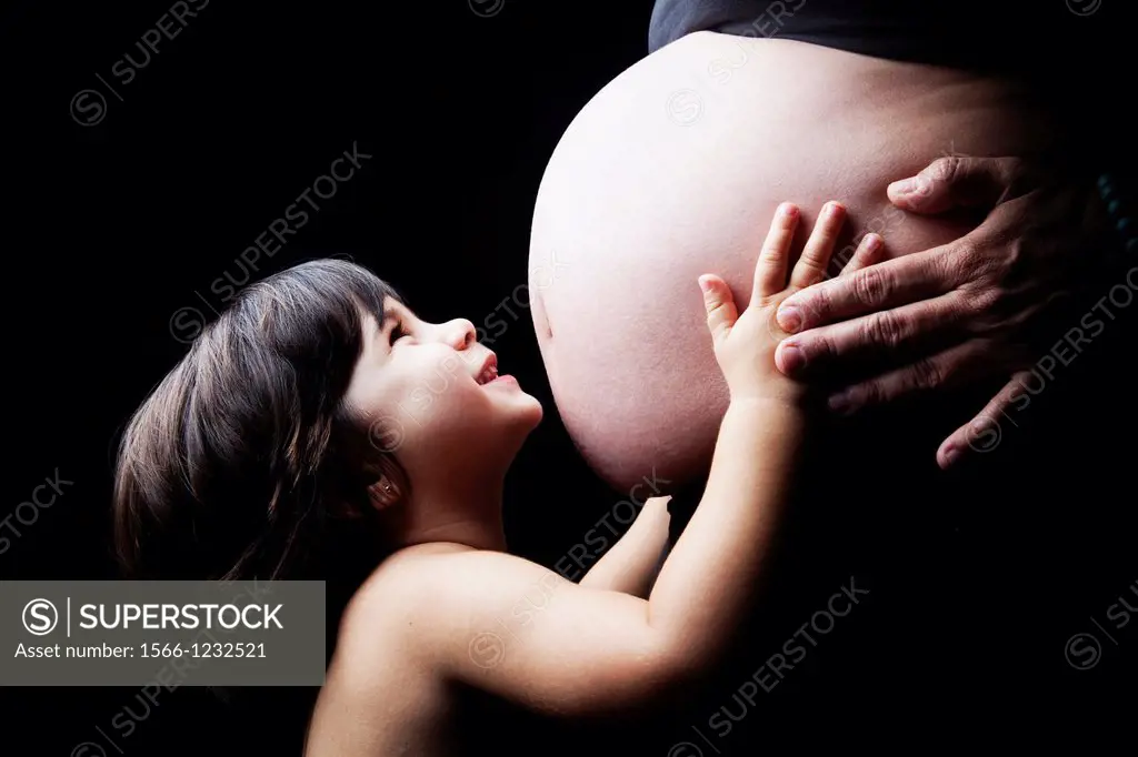 smiling girl embracing pregnant belly, Sevilla, Spain, Europe