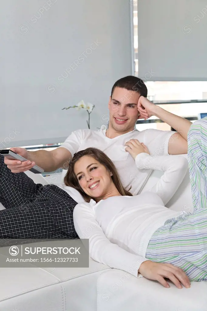 Happy young couple at sofa enjoying TV