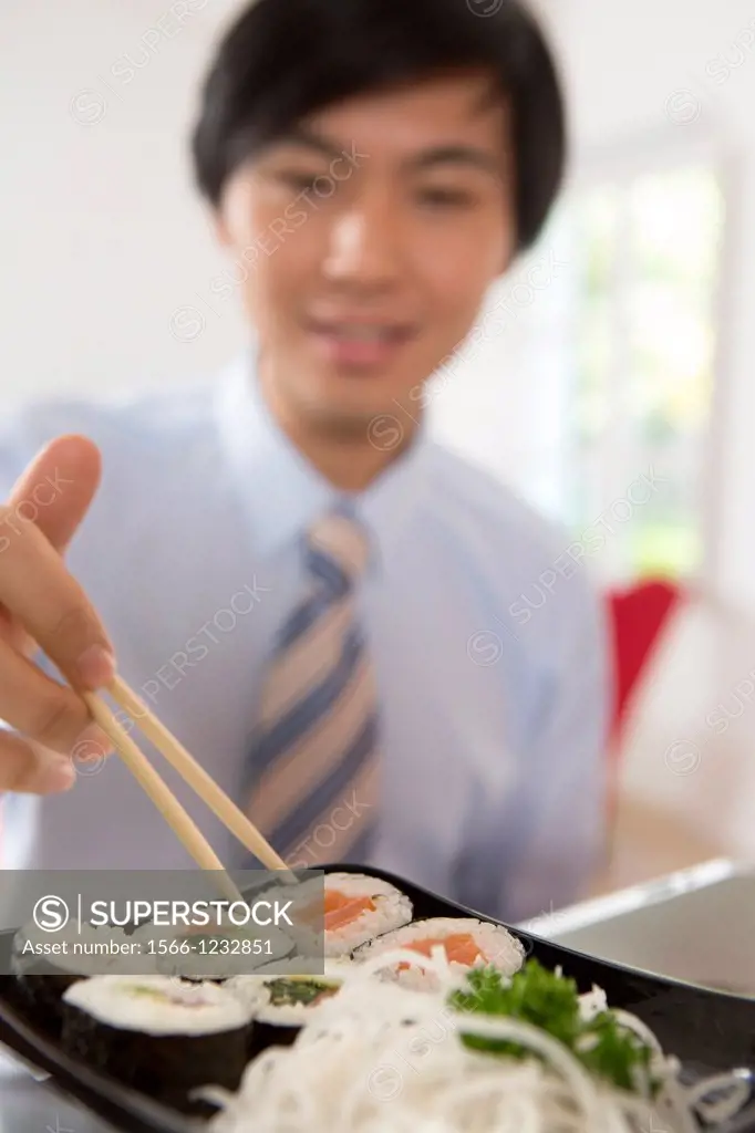 Young Asian businessman eating sushi
