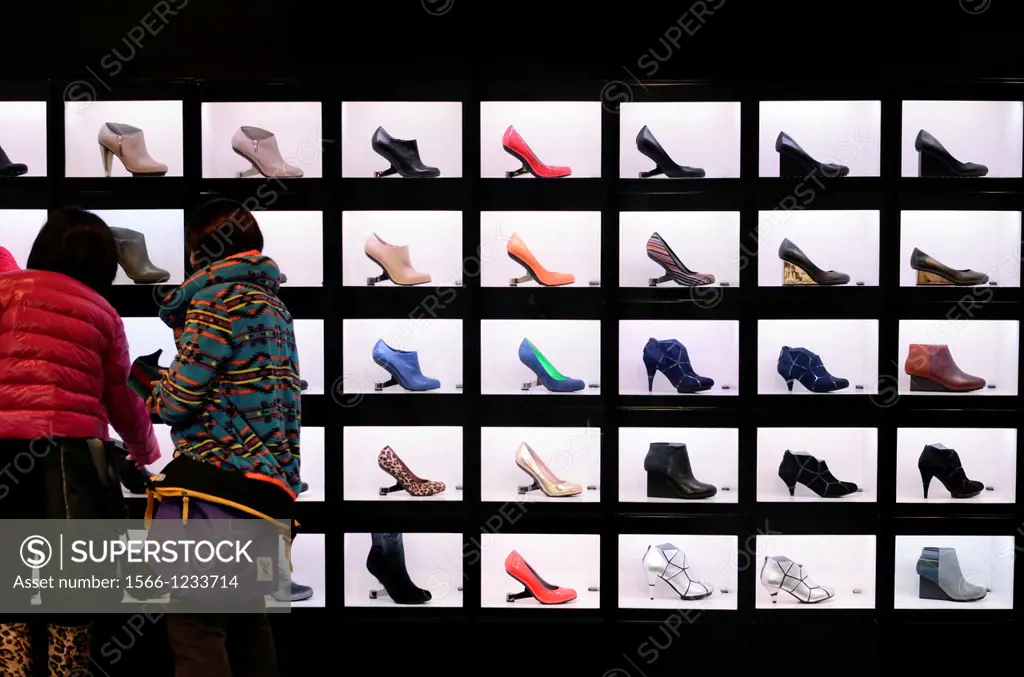 Female shoppers examining a shop display of brightly coloured shoes