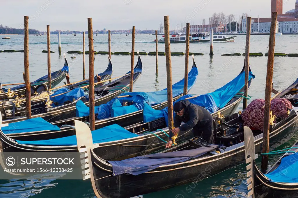 A gondolier preparing his gondola on Venice lagoon, Veneto, Italy, Europe.