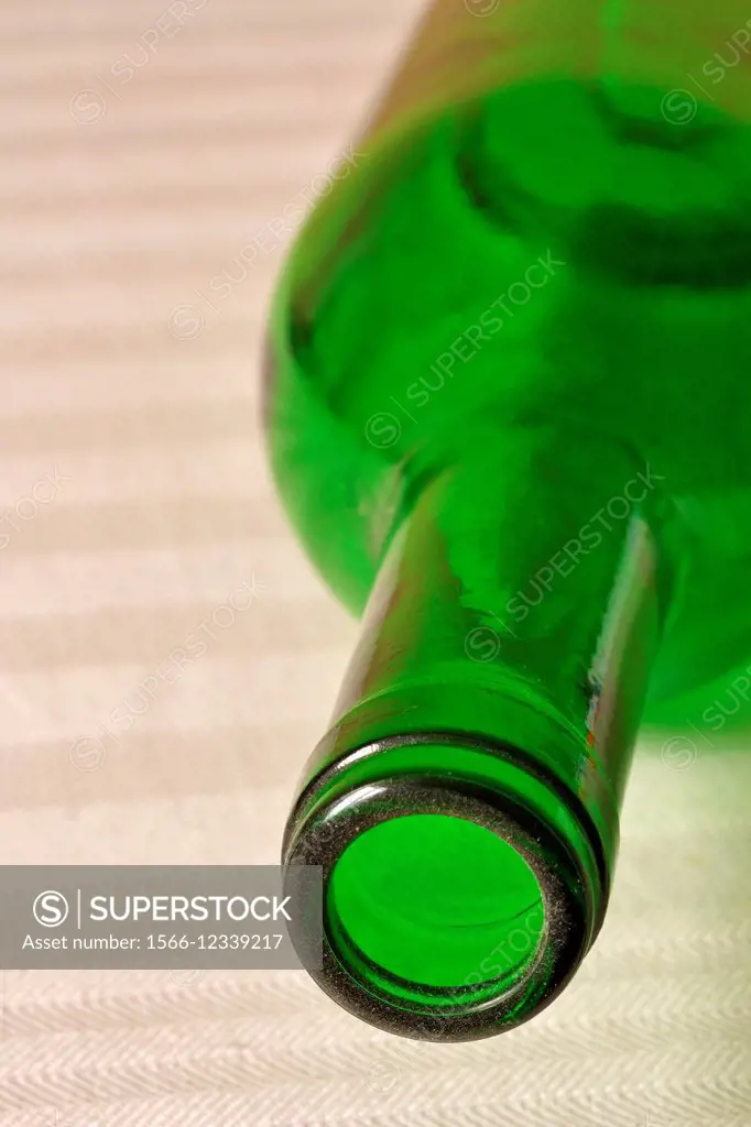 Green wine bottle laying on beige table cloth.