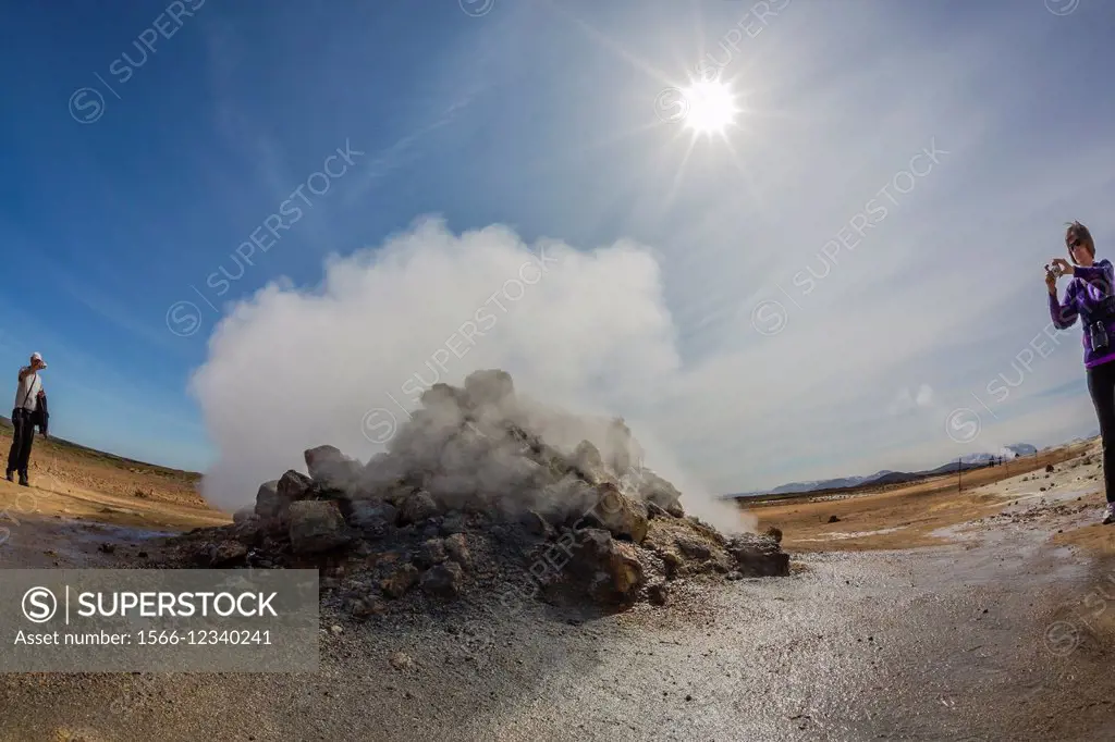 Photographer in geothermal field of mud pots, steam vents, and sulphur deposits at Hverarönd, Iceland.