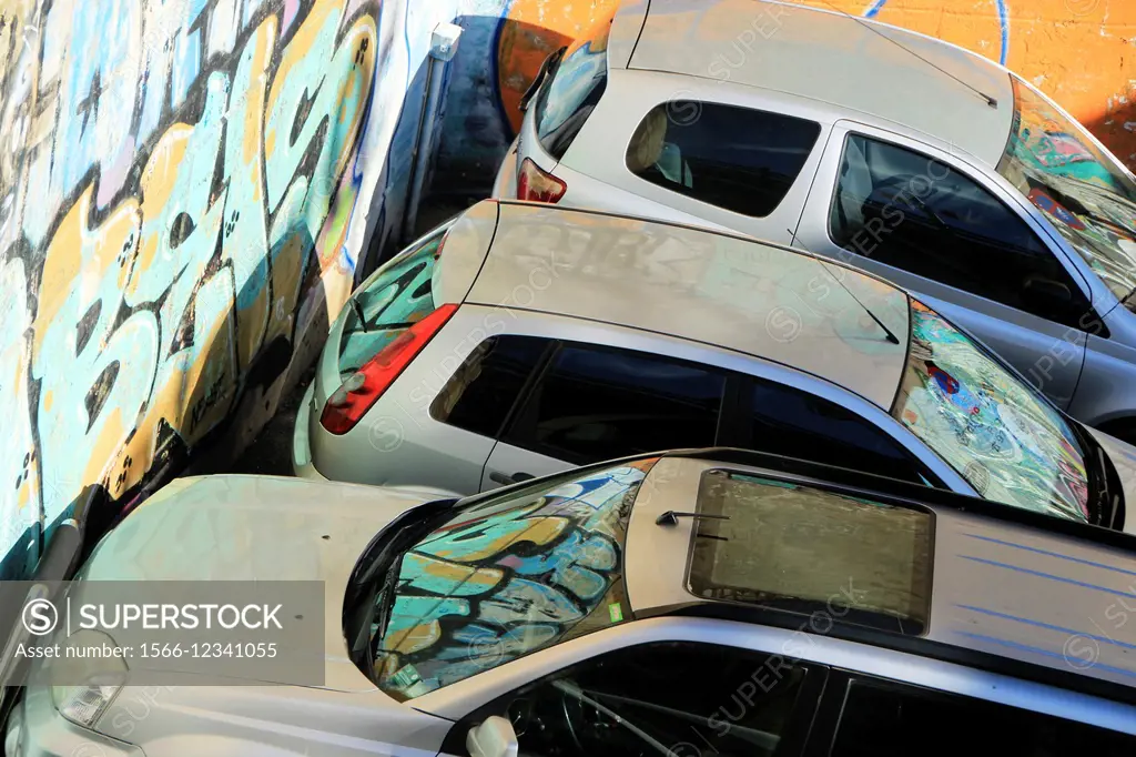 Cars parked in the street next to graffiti wall. Barcelona, Catalonia, Spain