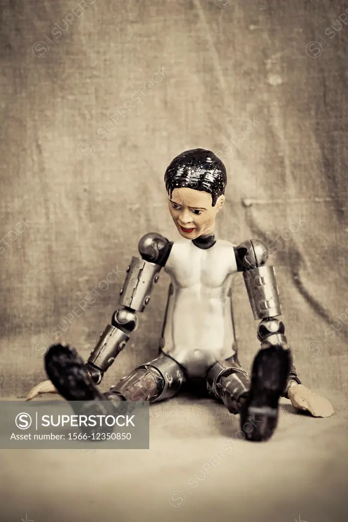 Pensive and depressed male toy doll sitting and looking down. Old fashioned retro design.