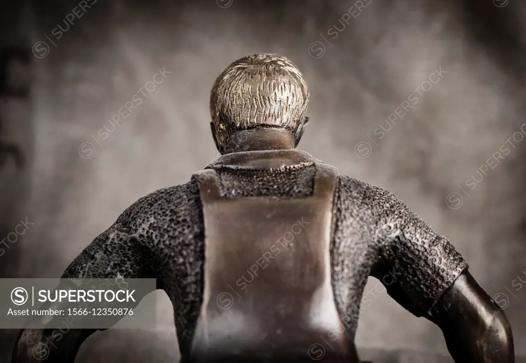 Back view of small metal sculpture of male worker.