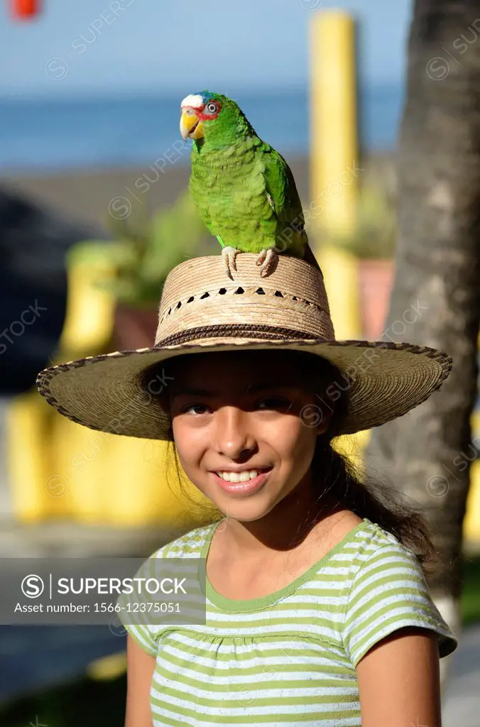 Portrait of a girl with a parrot on her head, Monterrico, Guatemala, Central America.