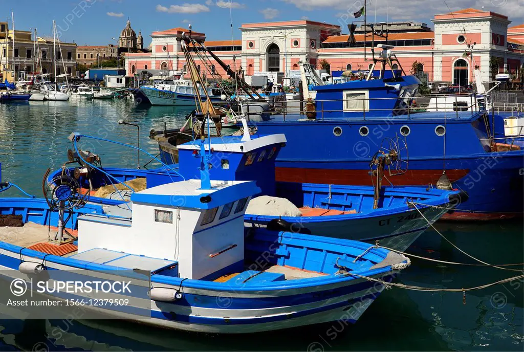 Catania harbour, fishing boats, old town and dome of famous Cathedral in far background, Sicily, Italy.