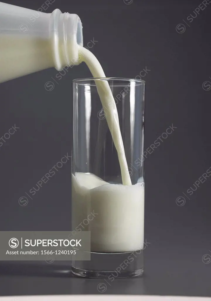 Glass and Bottle of Milk against Grey Background