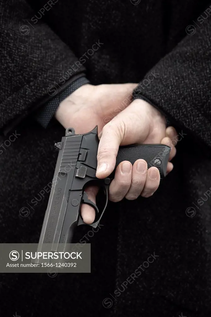 Man holding loaded gun behind his back
