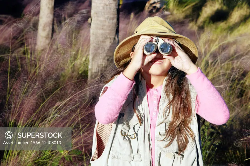 A young girl pretending to be on safari looking through binoculars.