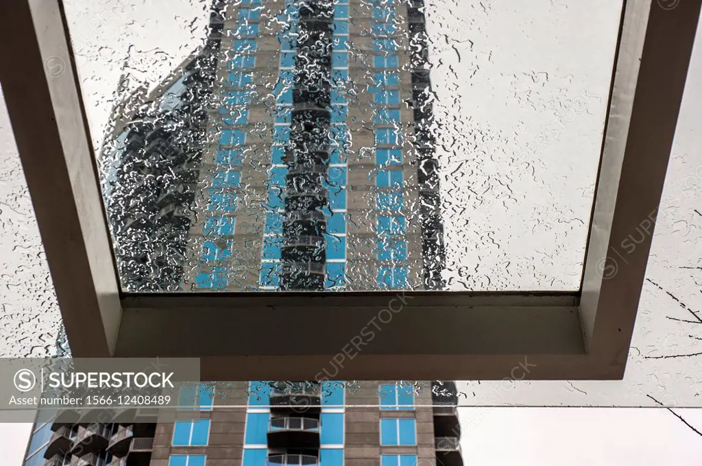 A glass awning with water drops with a building in the background.