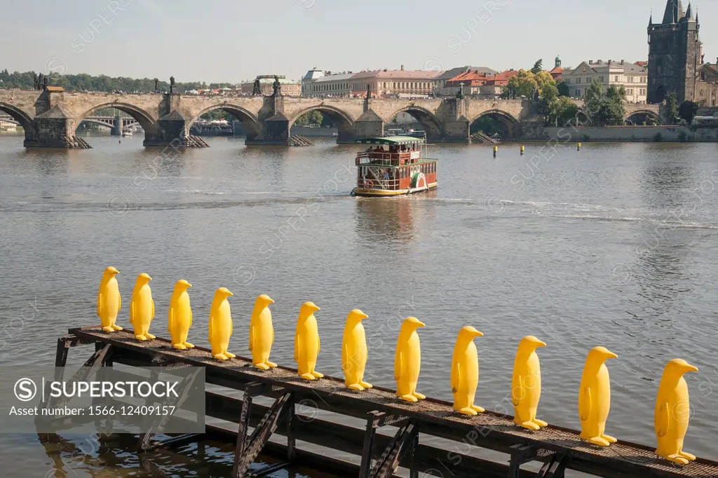 Yellow Penguin Sculptures outside the Kampa Museum with Vltava River and Charles Bridge, Prague, Czech Republic.