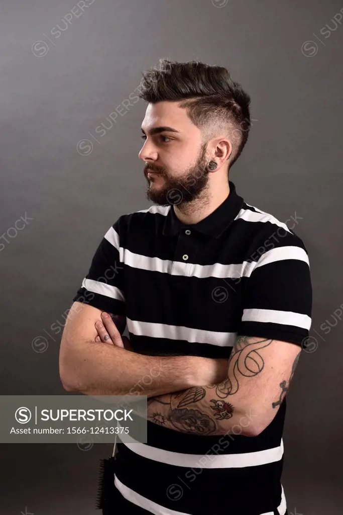 Portrait of a male hair stylist with tattoos and piercings.