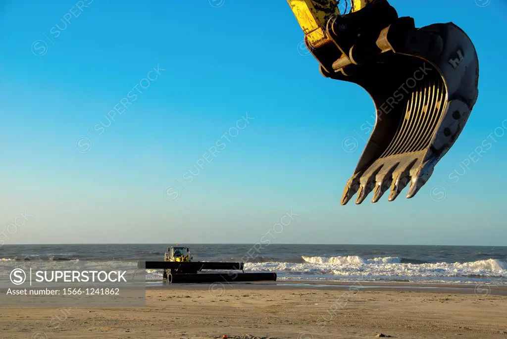 bulldozer and shovel preparing pipes for sand supply at beach in the Netherlands