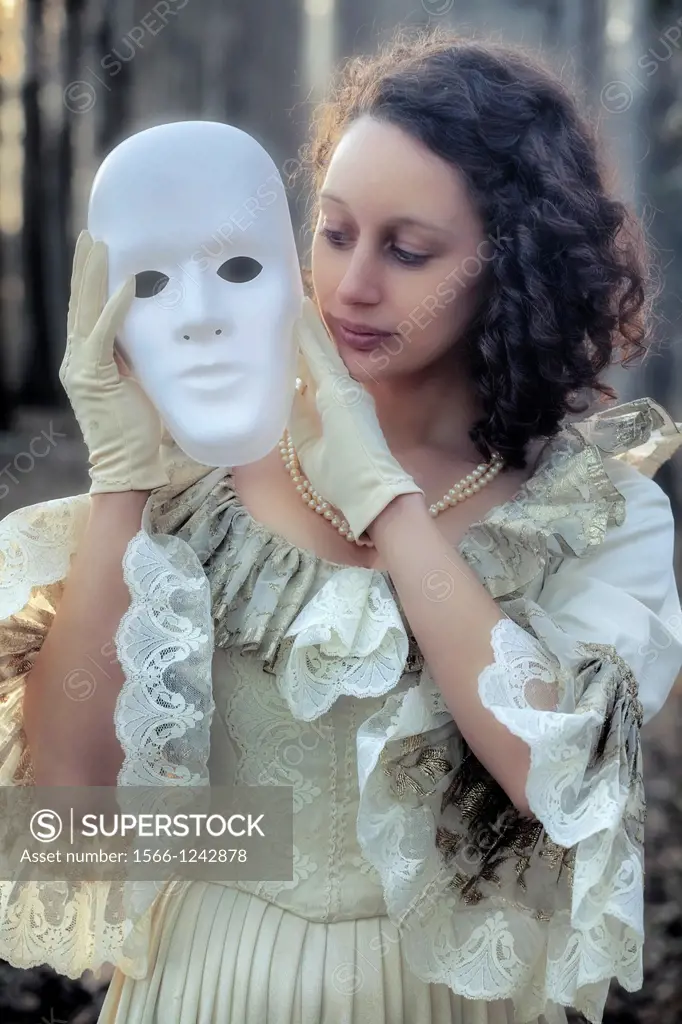 a woman in a period dress is holding a white mask