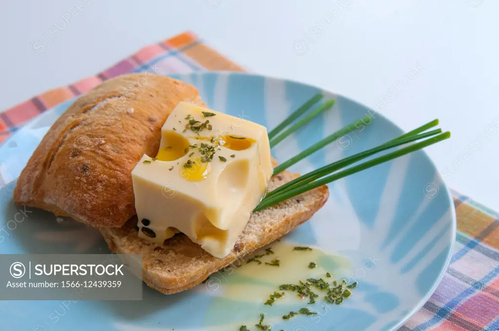 Maasdam cheese on bread with chives and olive oil.