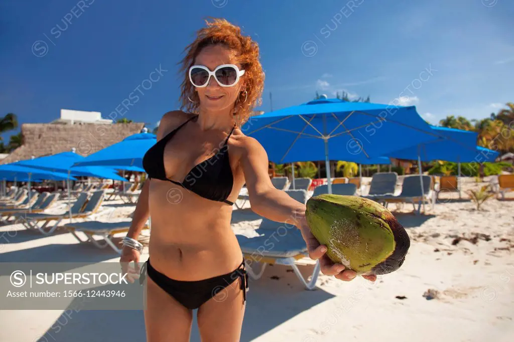 Woman holding a coco nut on the beach, Isla Mujeres, Cancun, Quintana Roo, Yucatan Province, Mexico, Central America.