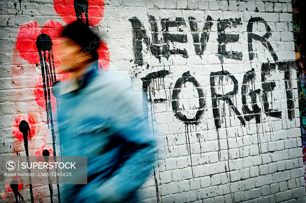 Never Forget graffiti, with man in motion in East London, London, England, UK
