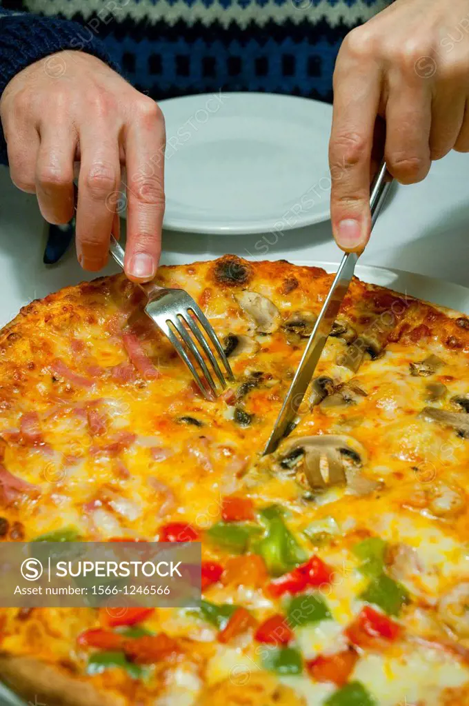 Man´s hand cutting a piece of pizza. Close view.