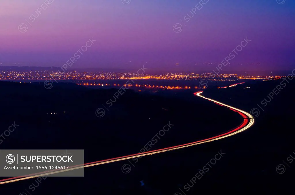 The M5 motorway and the lights of Weston-super-Mare viewed from Crook Peak on the Mendip Hills at dusk, Somerset, England