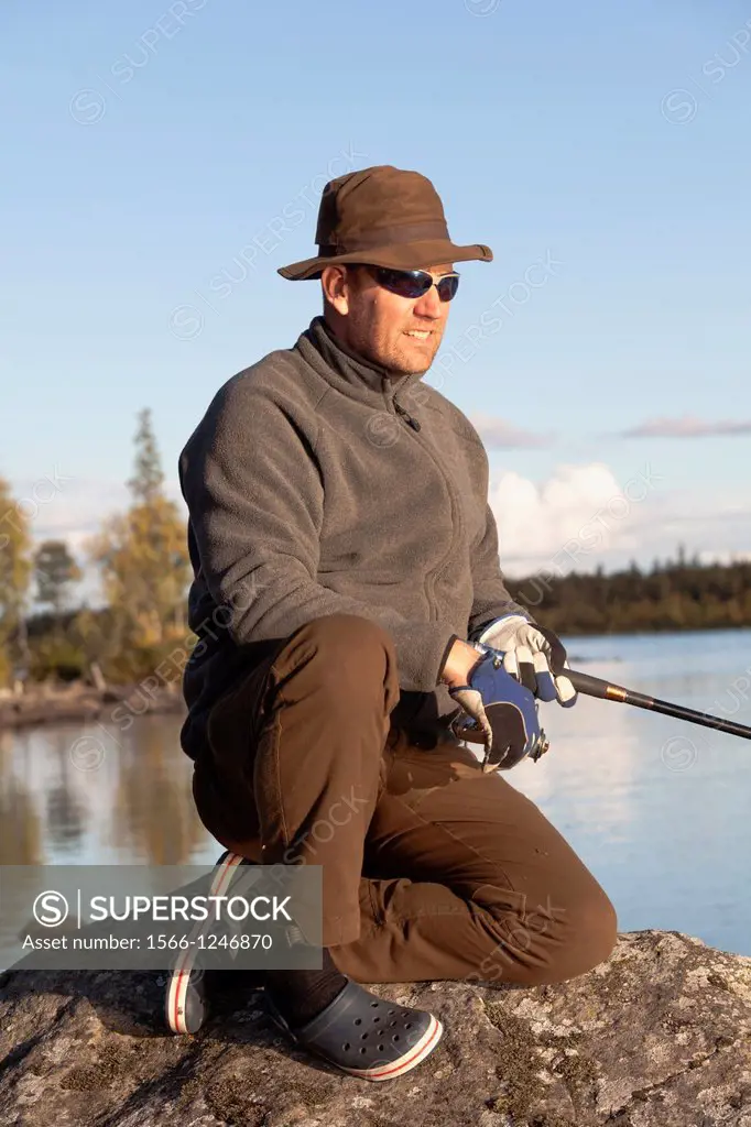 White man fishing in a river in swedish lapland in autumn season