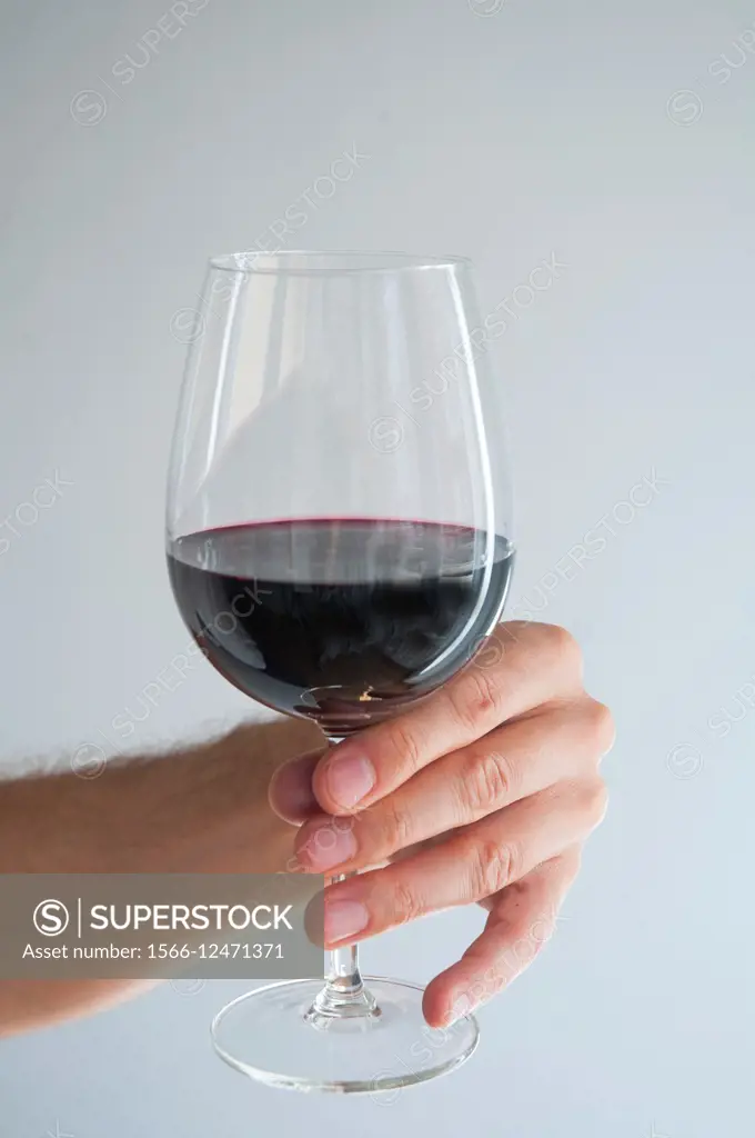 Man´s hand holding a glass of red wine. Close view.