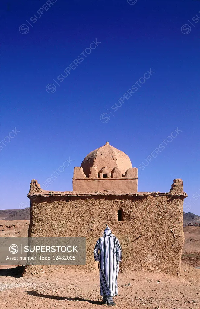 MOROCCO.SOUTH.OUARZAZATE.OLD MAN CLOSE TO AN ADOBE ""MARABOUT"" (MEANS A VAULTED HOLY MAN GRAVE SUBJECT TO PILGRIMAGES AND FAITH).