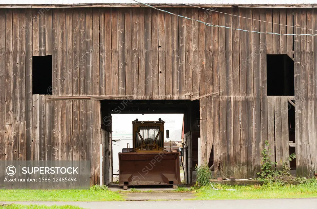 Canada, BC, Delta. Tractor with large shovel parked in barn. Farmland south of Vancouver