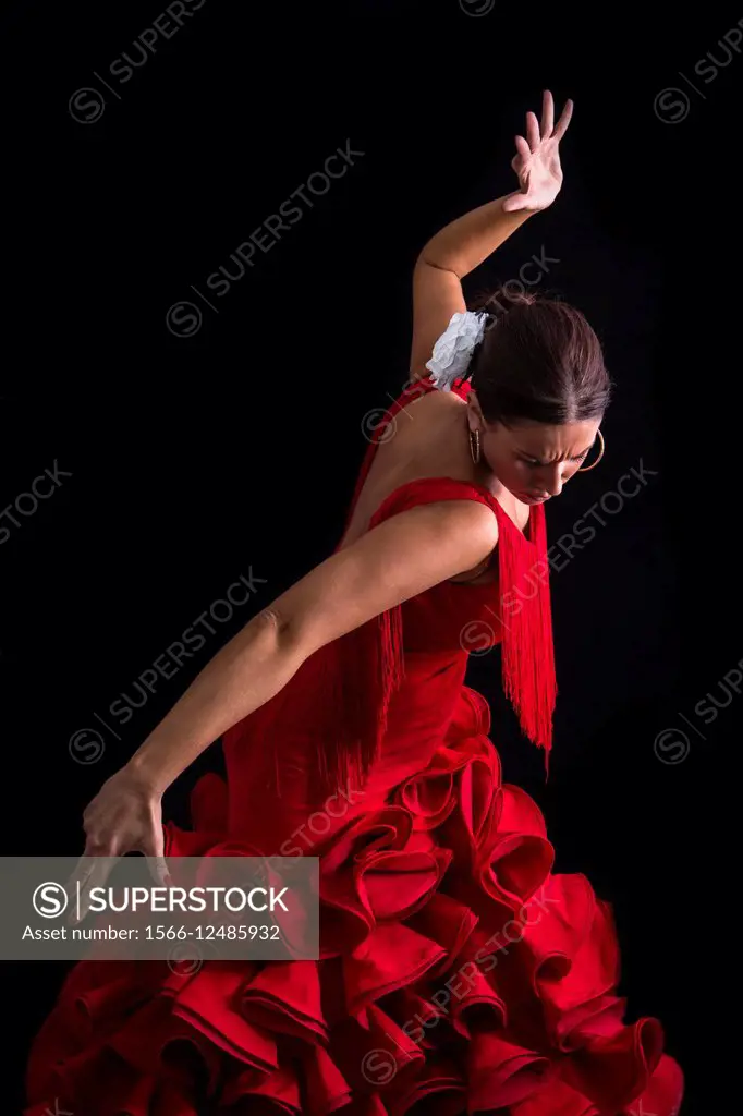 Flamenco dancer dressed in red with an expression of feeling passionate in black background.