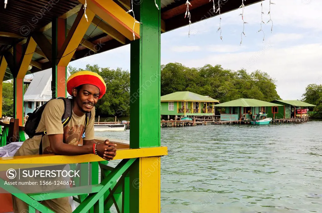 man leaning on the guardrail of an house on stilts at Cayo Coral, southern headland of Bastimentos Island, Bocas del Toro Archipelago, Republic of Pan...