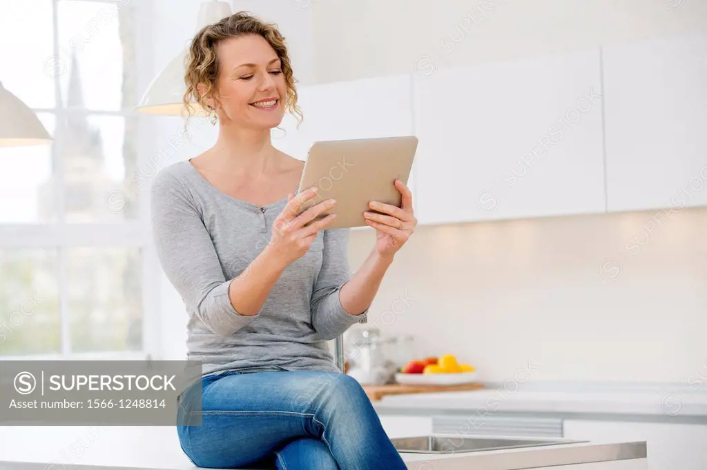 Attractive young woman communicating on her tablet computer at home