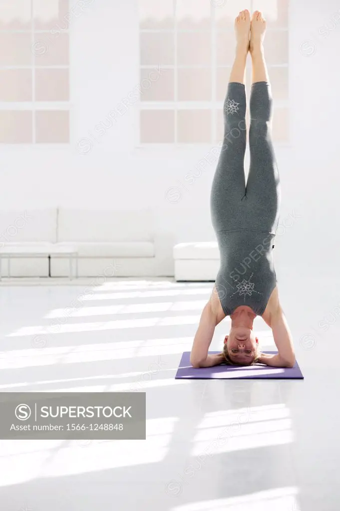 Healthy young woman doing the supported headstand yoga position