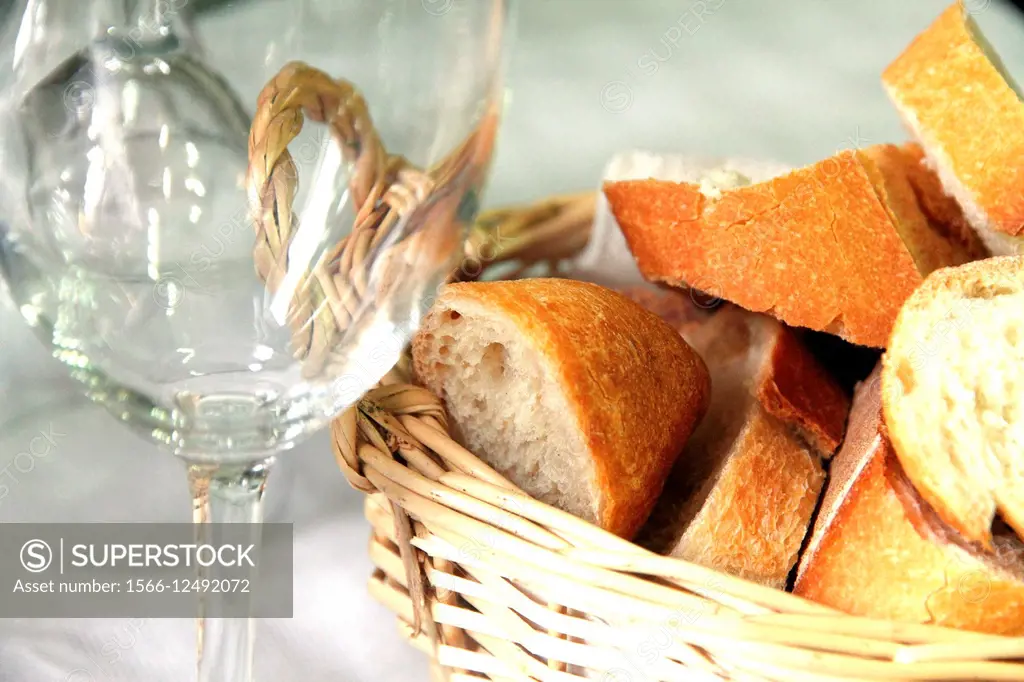 Empty glass and fresh crusty bread in a basket.