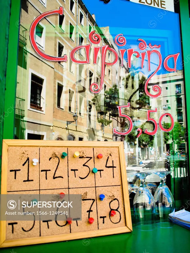 Caipirinha reflected on the glass of a window. Numbers written on wooden ceiling. Cups.