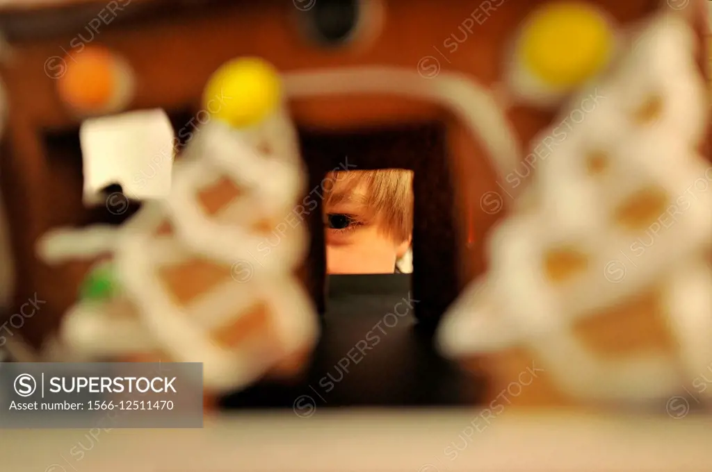 Boy looking through window of gingerbread house at Christmas. Stockholm, Sweden