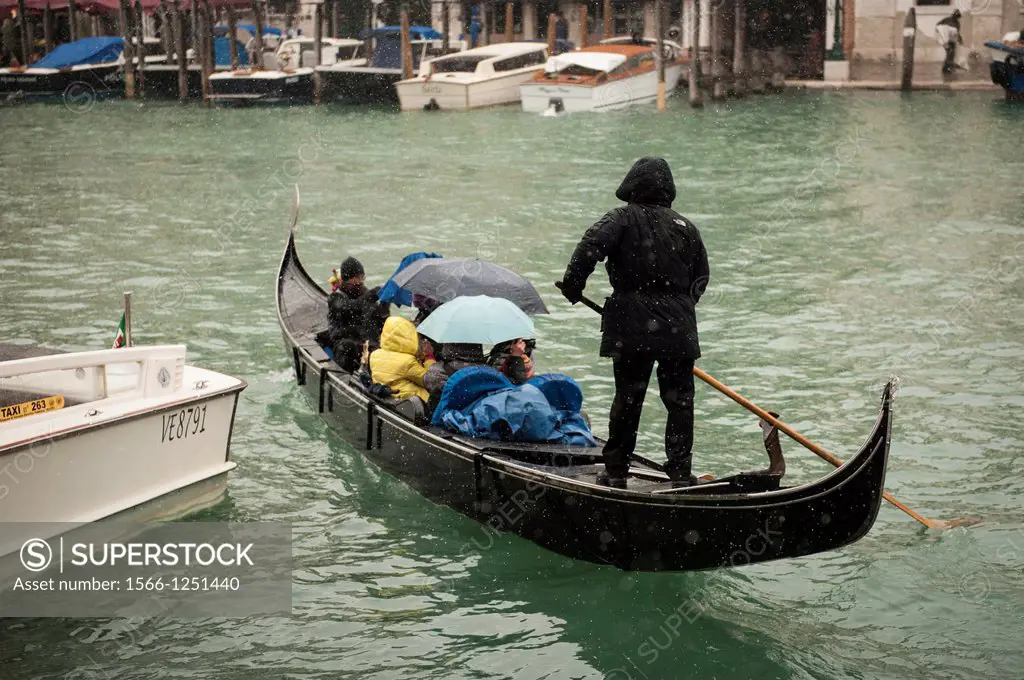 A gondolier takes tourists for a gondola ride during a heavy snowfall in Venice, Italy.