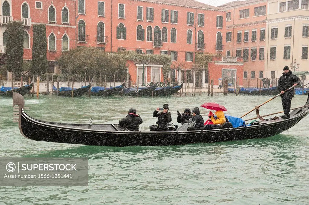 A gondolier takes tourists for a gondola ride during a heavy snowfall in Venice, Italy.