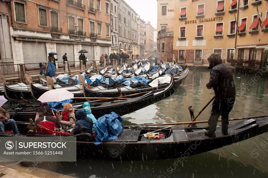 A gondolier takes tourists foir a gondola ride during a heavy snowfall in Venice, Italy
