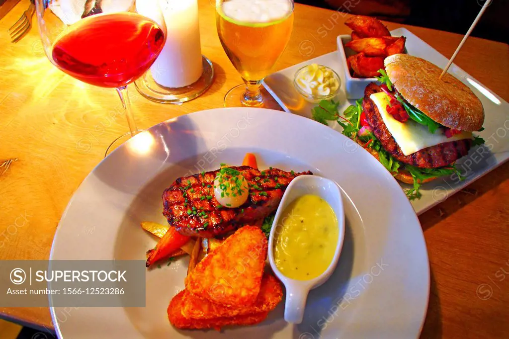 Ribeye English beef steak and hamburger with wine and beer in a tavern, Copenhagen, Denmark
