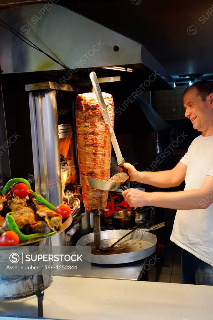 Man slicing roasted lamb from a Gyro heated by a vertical wood oven in Antalya Turkey