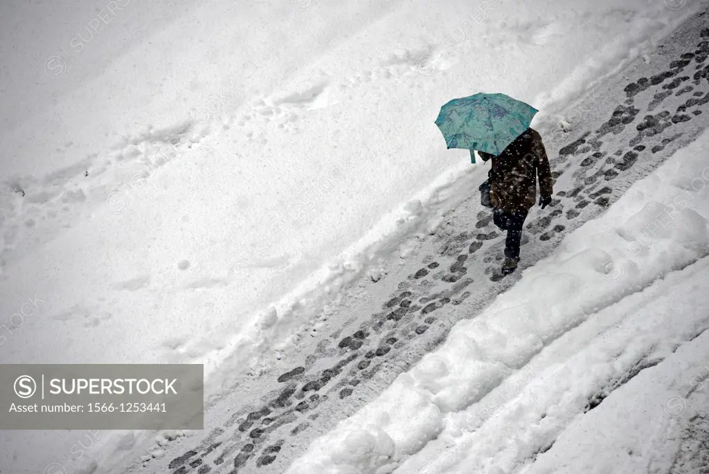 snowed street, man walking under umbrella, snowfall, winter in Geneve, Switzerland