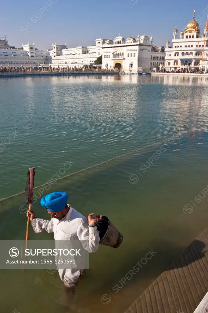 Sikh man clearing debris from the lake, Sikh Pilgrim, The Golden Temple of Amritsar, aka The Harmandir Sahib or Hari Mandir Punjab, India
