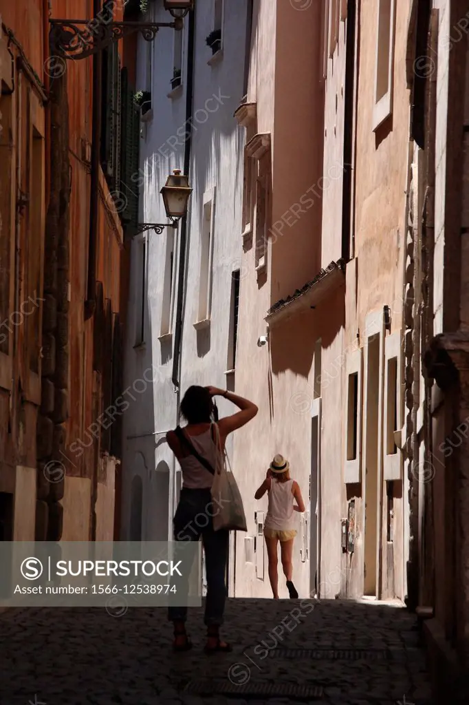 young woman tourist taking photograph in street road in the Santa Angelo district near the Jewish ghetto in Rome, Italy.