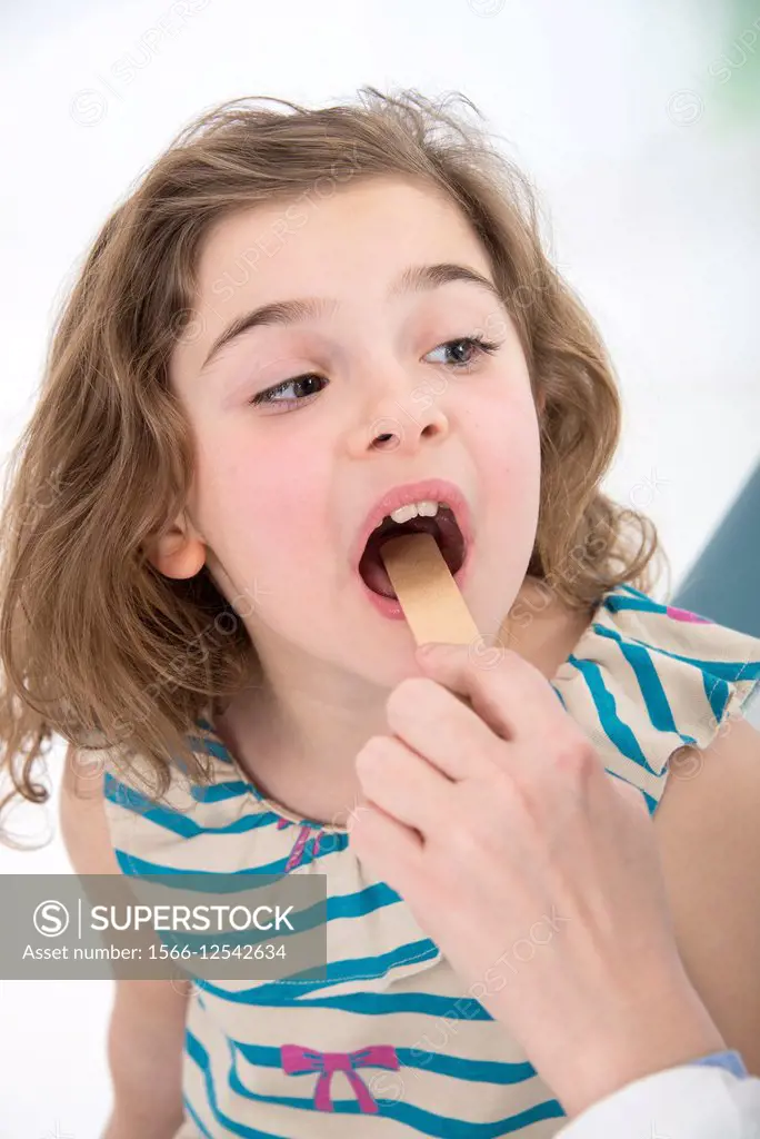 Hand of doctor pediatrician examining mouth and throat of little girl with a spatula