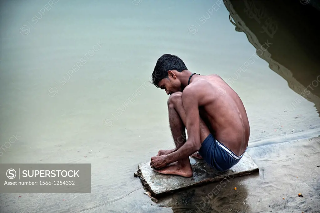 Young man preparing a fish hook at the riverbank of the Ganges rives  Varanasi, Benares, Uttar Pradesh, India