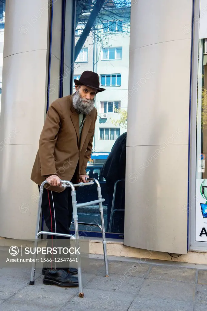 Blvd. Kniaz Aleksander Dondukov, Sofia, Bulgaria. Elder man with walker - walking aid, slowly taking a strawl through the streets of Sofia.