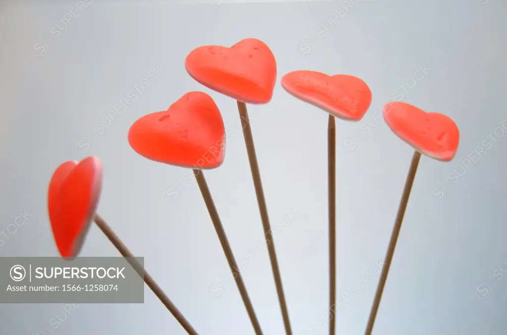 Five red hearts over wooden poles, gray background.
