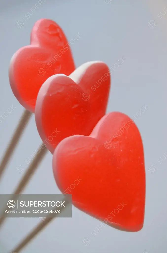 Three red hearts over wooden poles, gray background.
